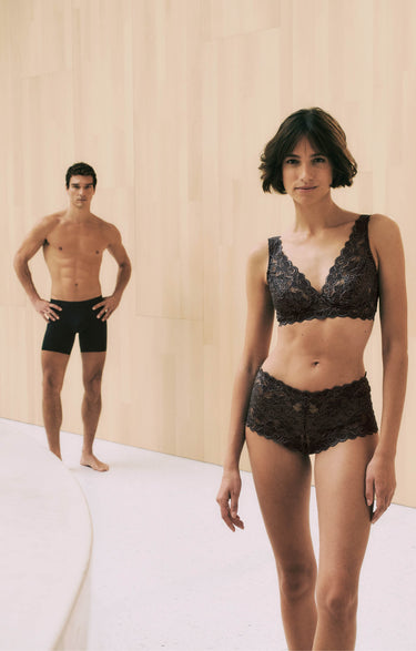 Man and woman wearing black lingerie against a neutral background